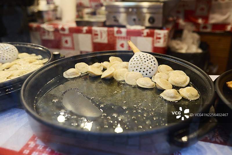 波兰弗罗茨瓦夫市场摊位上，波兰饺子在平底锅中烹饪图片素材
