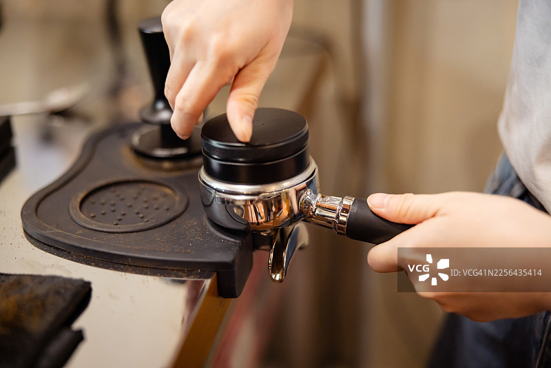 咖啡店里，一位女性咖啡师正在冲泡新鲜的意式浓缩咖啡。图片素材