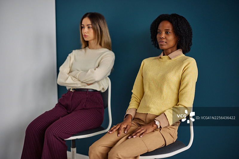 两位女性坐在现代工作室的椅子上，营造出平静而专业的氛围图片素材