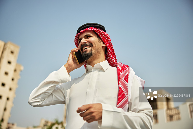 仰拍沙特男子使用手机的抓拍肖像图片素材