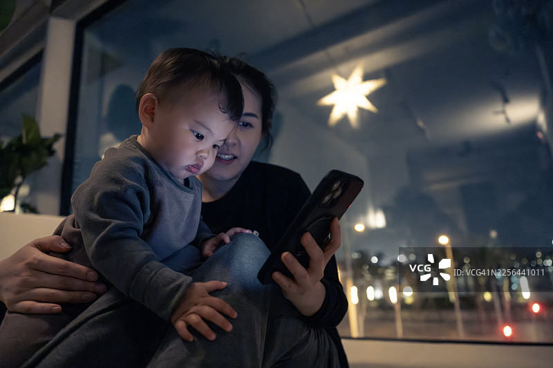 11个月大的婴儿和妈妈一起看着手机屏幕图片素材