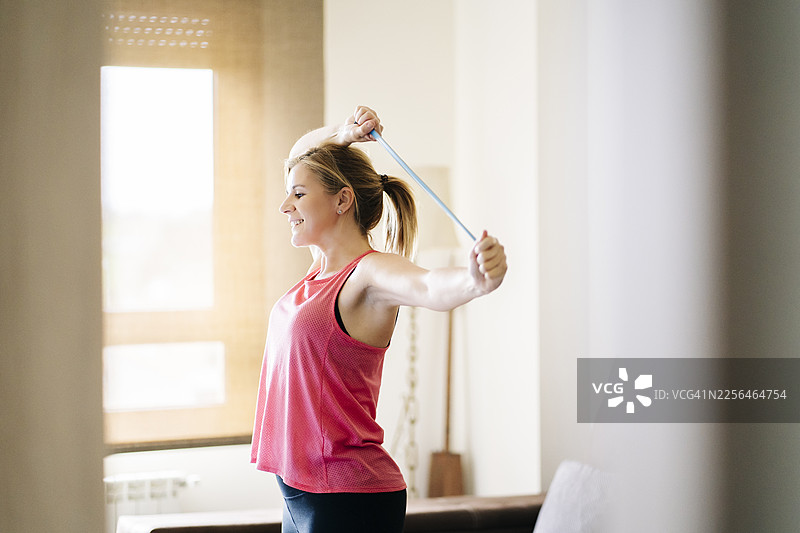女子在家中使用弹力带锻炼手臂图片素材