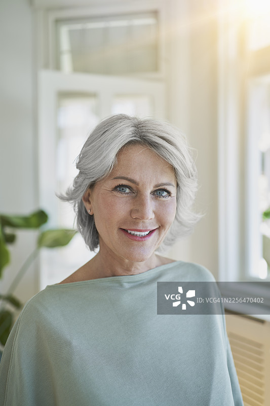 一位白发女士在明亮的客厅里微笑着图片素材