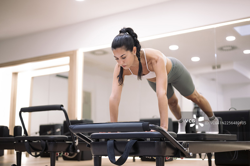 在现代健身房用普拉提训练器锻炼的人图片素材