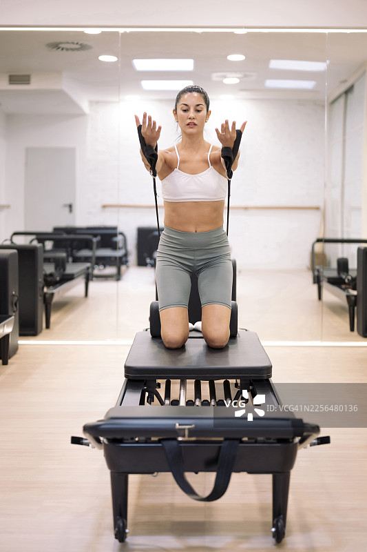 一个人跪在普拉提器械上，在现代健身房工作室锻炼图片素材