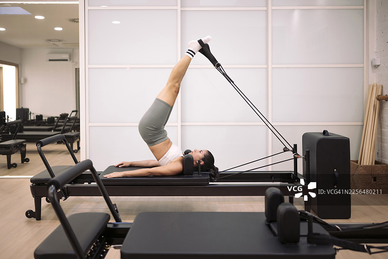 女子在室内使用普拉提器械进行锻炼图片素材