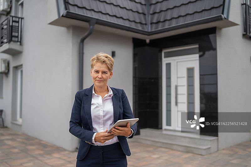 一位成熟的女性房地产经纪人在建筑物外拍摄肖像图片素材