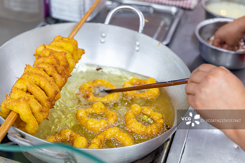 特写镜头：手在大锅里用热油炸传统小吃图片素材