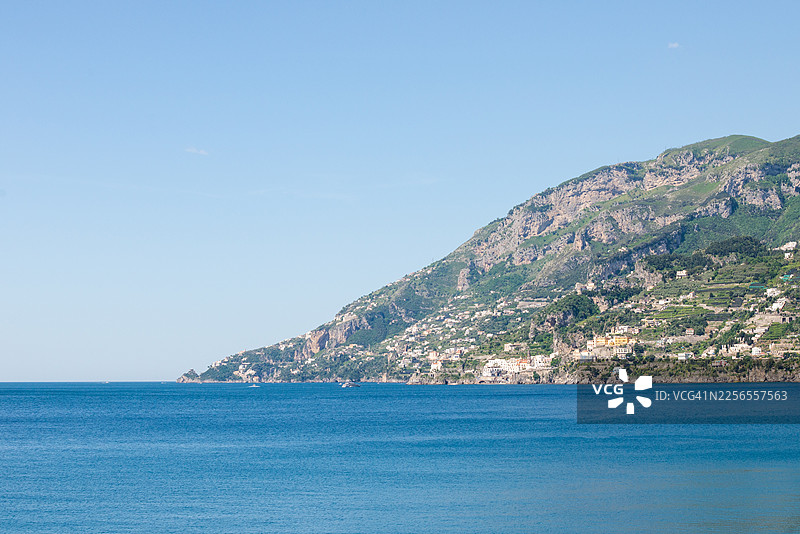 阳光明媚的日子里，蔚蓝大海与晴朗天空下的阿马尔菲海岸风景图片素材