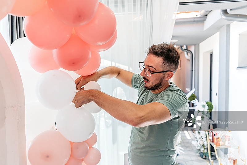 中年男子为生日派对布置气球图片素材