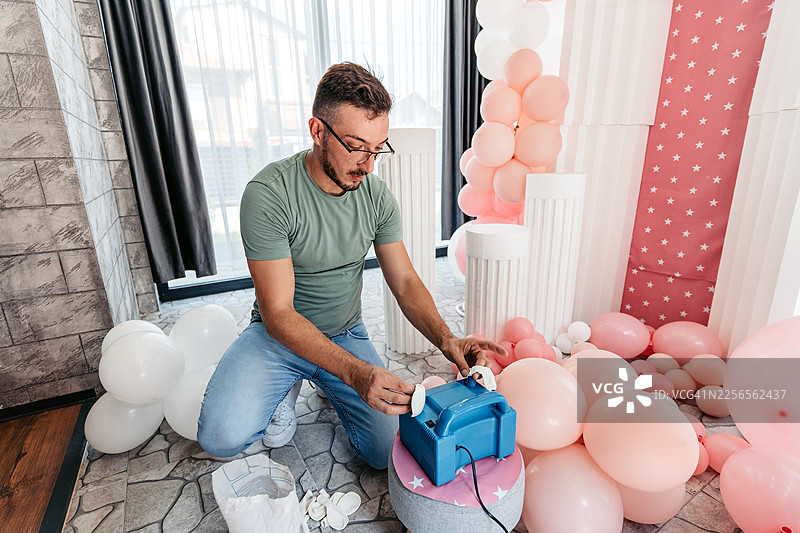 中年男子使用打气筒为生日派对充气球图片素材