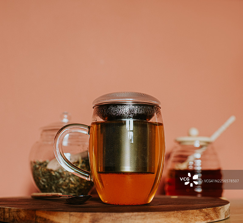 木质台面上的玻璃茶杯，内嵌茶漏，盛满琥珀色茶水。图片素材