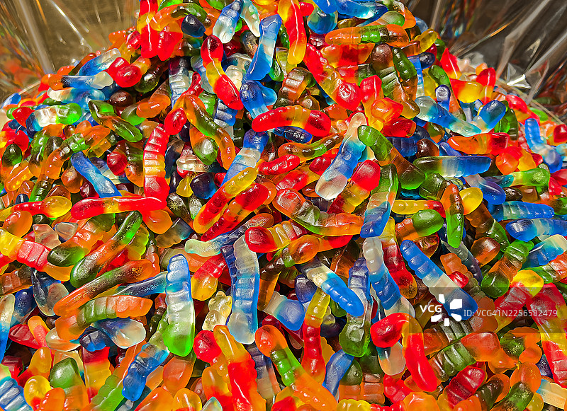 一堆色彩鲜艳的软糖，呈小蛇形状，颜色各异，如同彩虹一般。图片素材