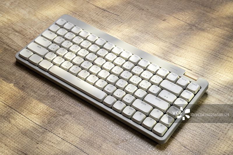 阳光照射下的白色复古机械键盘放在木桌上图片素材