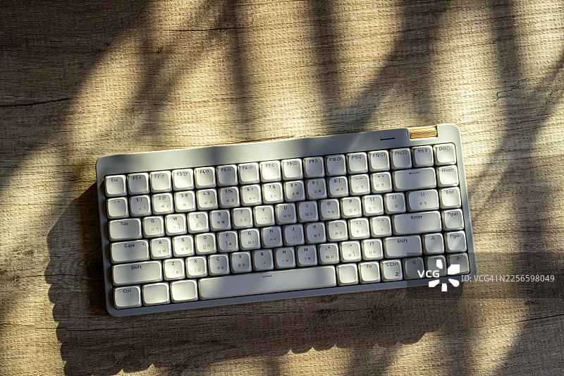 阳光和阴影下的木桌上的机械键盘图片素材