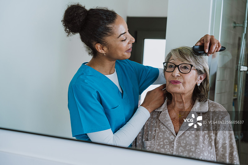 护理人员在浴室中协助老年人在家打理头发图片素材