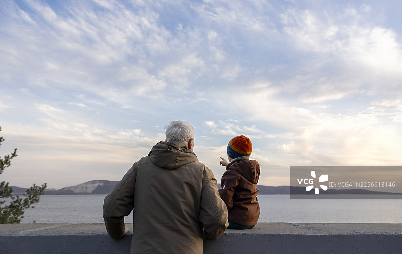 爷爷和孙子在户外欣赏秋季河岸风光图片素材