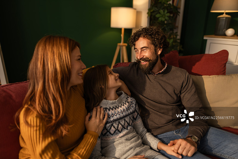 快乐的一家三口在沙发上放松聊天图片素材