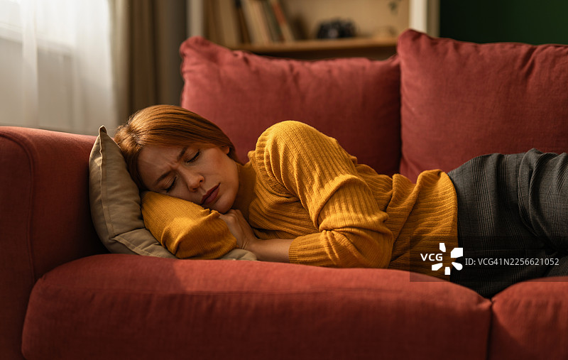 一名患有抑郁症的女子躺在沙发上，感到悲伤图片素材