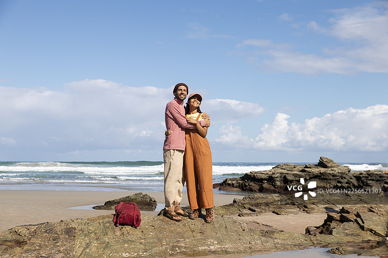 情侣在加利西亚拉斯卡特德拉莱斯海滩的岩石上拥抱图片素材