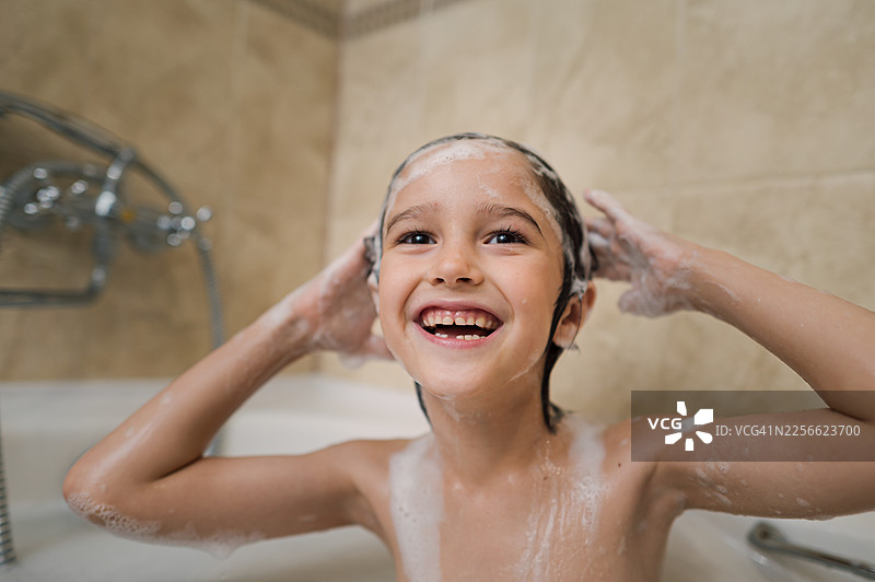 快乐的孩子在浴室里用泡沫洗头发图片素材