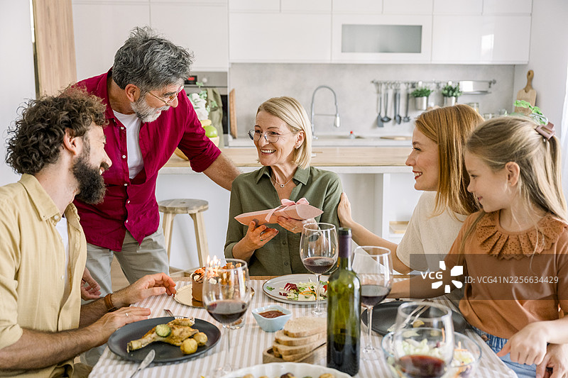 一家人在温馨的厨房里庆祝生日，有蛋糕和礼物图片素材