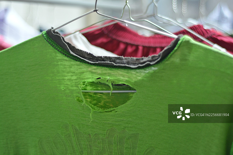 特写：挂在户外衣架上的破损衣物图片素材