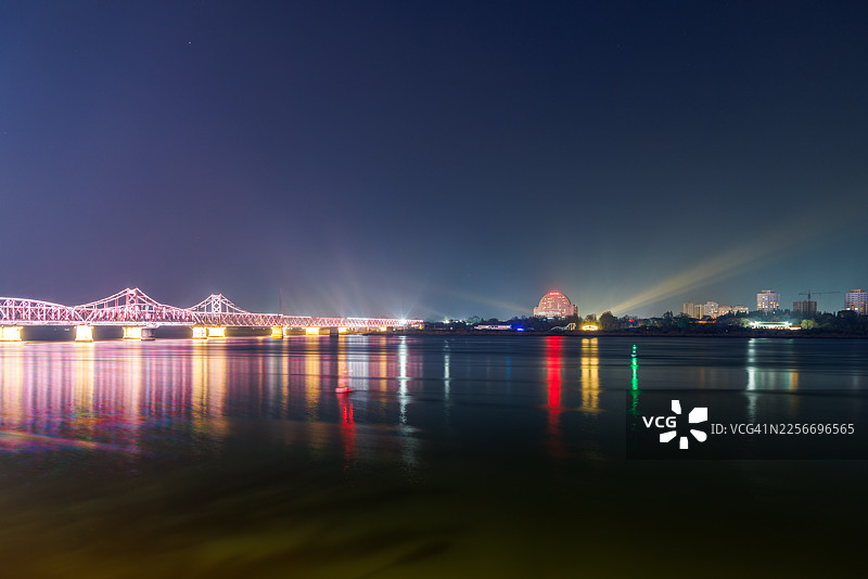 鸭绿江大桥夜景，对岸是新义州市。边境城市灯火，国际边界，以及对比鲜明的城市夜景图片素材