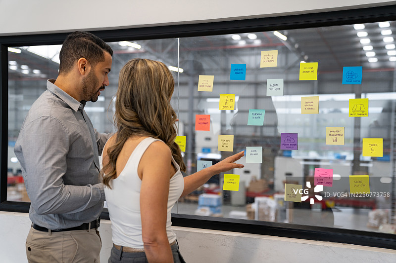 商务团队在仓库内整理货物时，指向便利贴图片素材