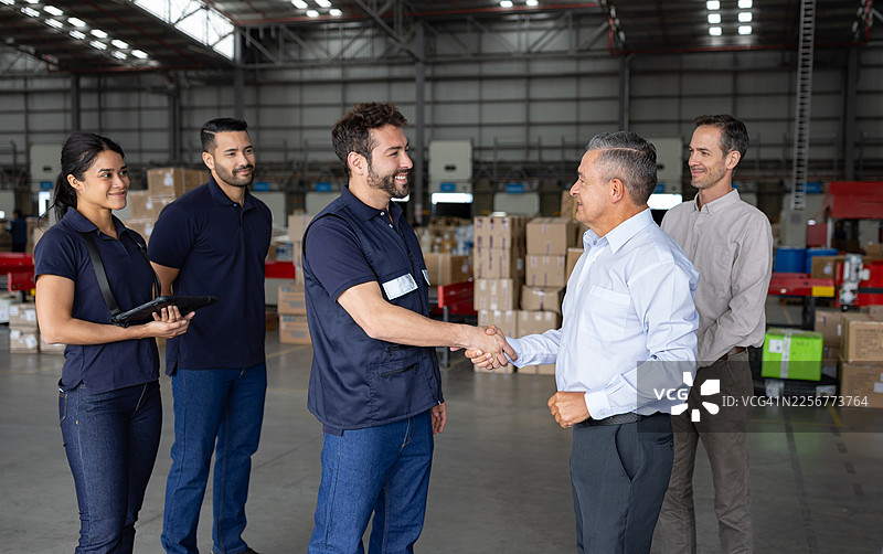 分销仓库里的员工与企业主握手致意图片素材