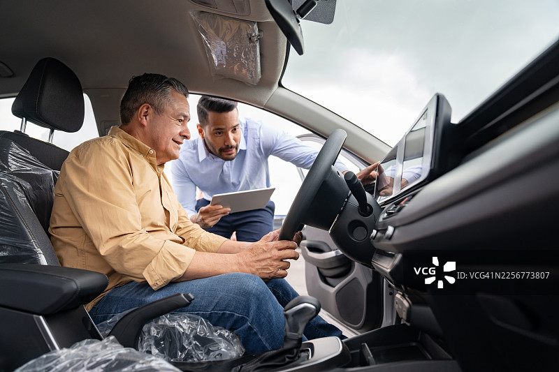 销售人员向在经销商处购车的男士展示一辆汽车图片素材