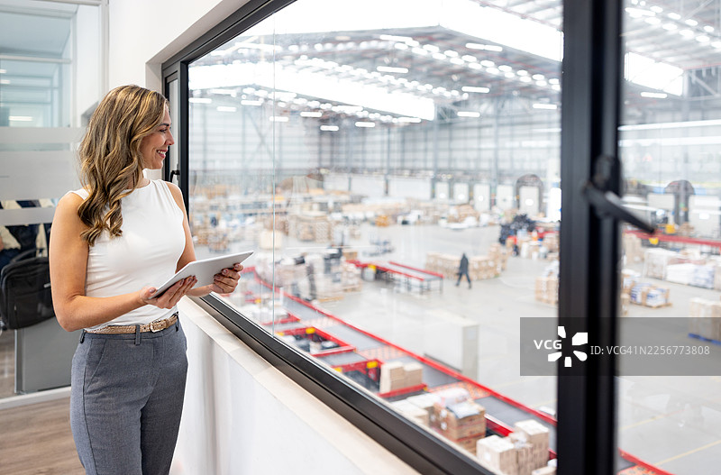 一位女商人正在物流仓库的办公室里使用平板电脑工作图片素材