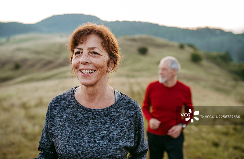 年长夫妇在户外运动训练，穿过草地奔跑图片素材