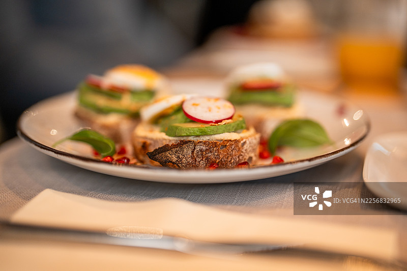 盘中盛放着令人食欲大开的早午餐吐司小点，上面有牛油果和萝卜图片素材