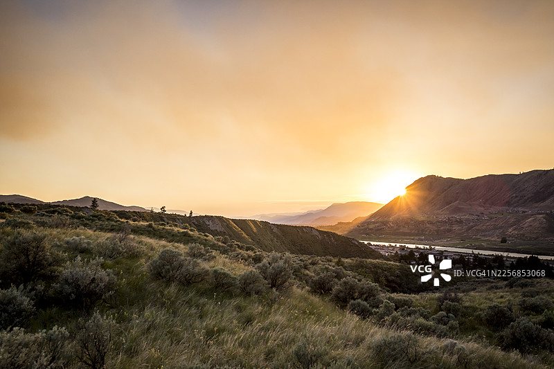 卡姆卢普斯，日落下的山脉、河流、城镇和草甸图片素材