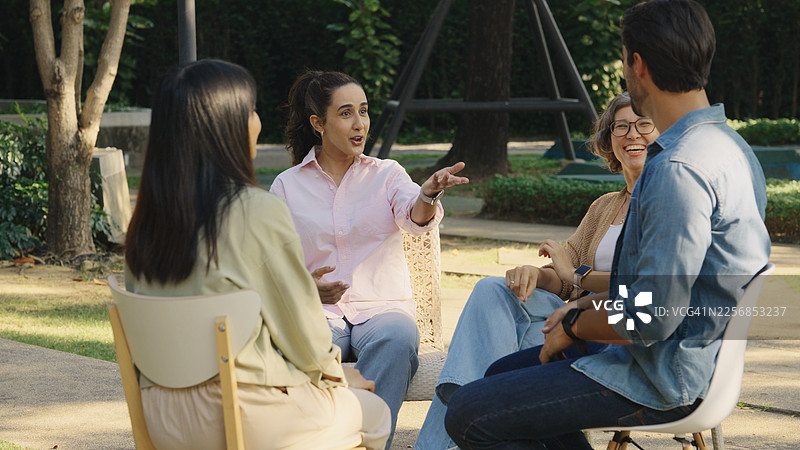 一群人在绿色的公园里围坐在一起，舒适地交谈，进行支持性会议、心理治疗培训，分享心理健康团体治疗过程中的经验，以促进治愈和福祉。图片素材