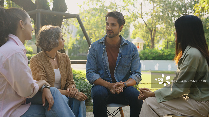 一群人在绿色公园里围坐在一起，舒适地交谈，进行支持性会议、心理治疗培训、心理健康团体治疗课程中的经验分享、疗愈与身心健康图片素材