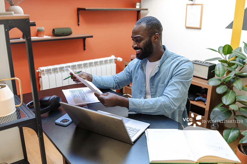 男人在家工作，在整洁的办公桌上用笔记本电脑和文件整理税务图片素材
