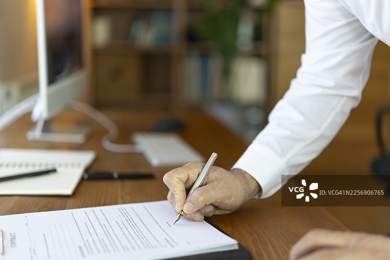 成熟的成年人手持钢笔签署商业合同图片素材