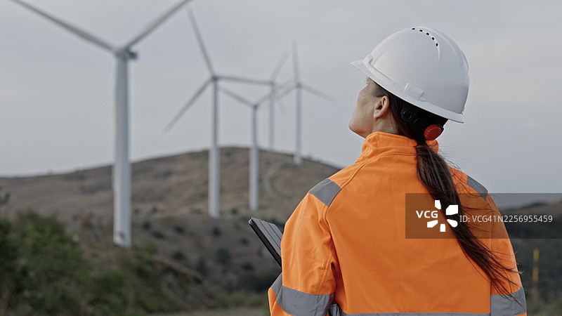女性工程师在风力发电场使用平板电脑。可再生能源图片素材