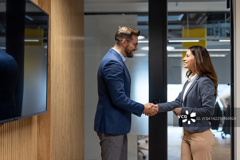 两位商务人士在现代办公室握手图片素材