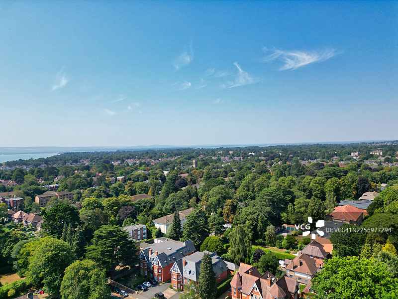 从高处俯瞰，绿色的城镇风光，房屋与树木点缀其间，在晴朗的蓝天下延伸至大海，英国伯恩茅斯，马尔伯勒路图片素材