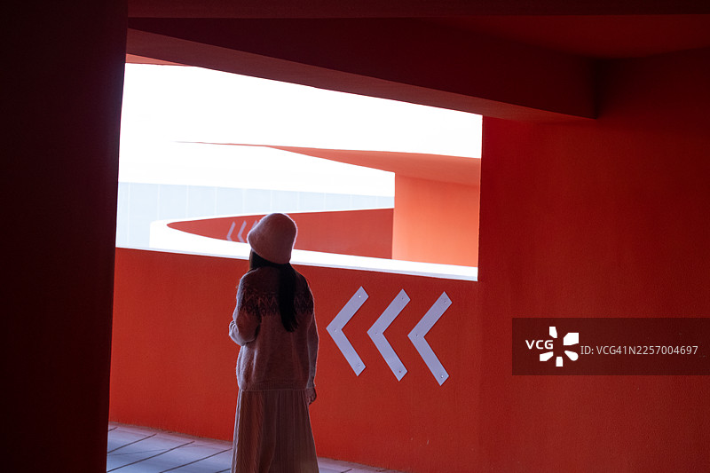 女子站在停车场，眺望着远方的天空。图片素材