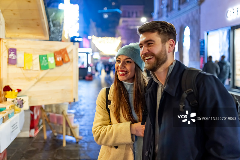一对情侣在夜市的节日街景中，享受着温暖和欢笑图片素材