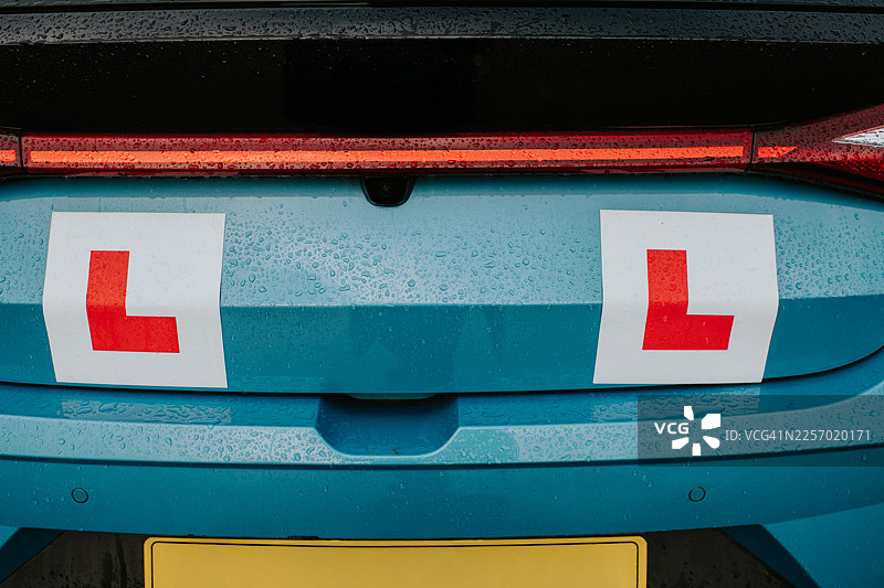 后视镜中的教练车，车尾张贴着L牌图片素材