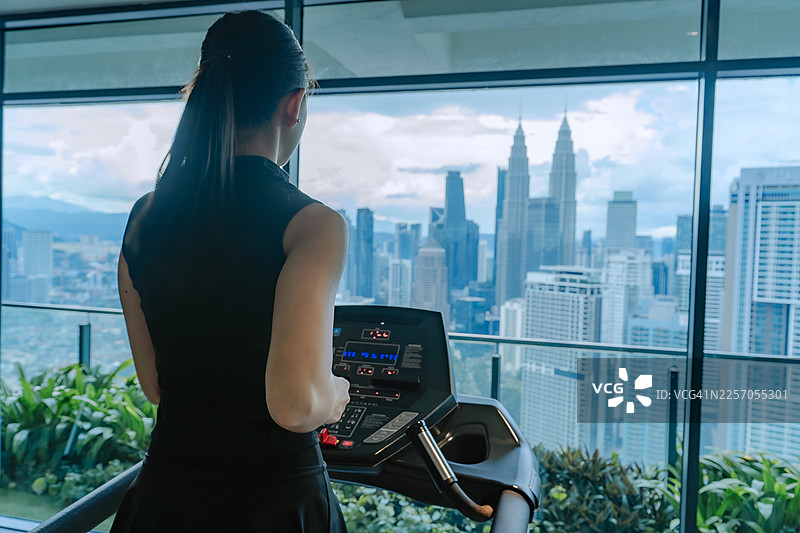俯瞰城市天际线的跑步机上奔跑的女性图片素材