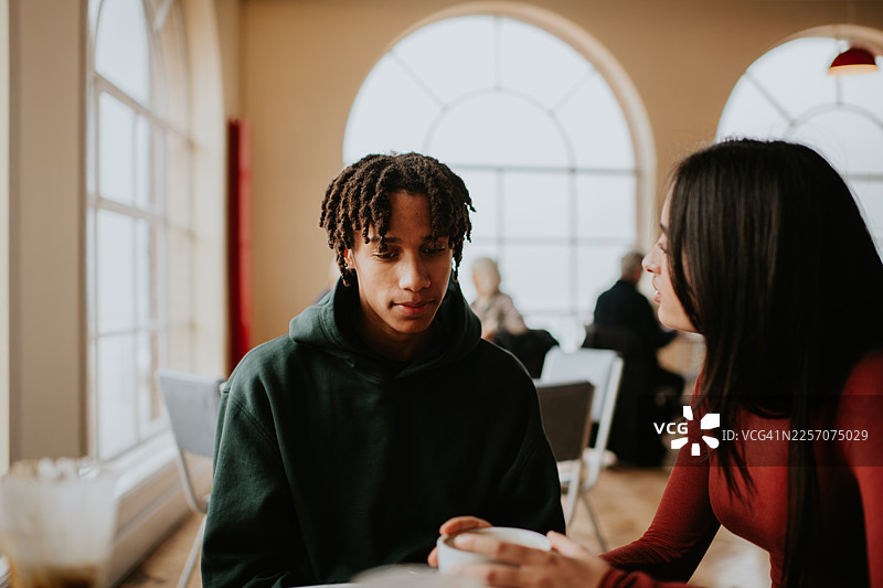 一位年轻男子在向一位年轻女子倾诉，女子在一旁倾听。图片素材
