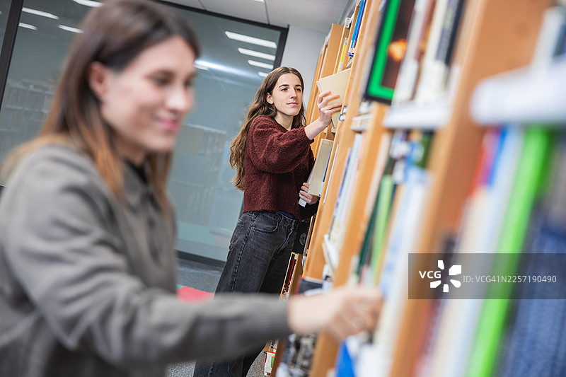 大学生在大学图书馆挑选书籍图片素材