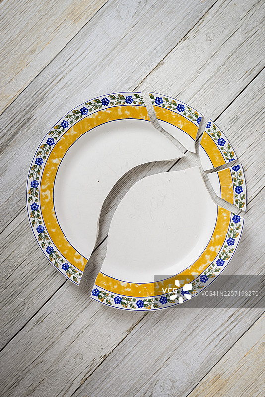 木桌背景上摔碎的陶瓷盘子图片素材