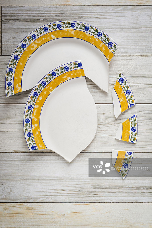 木桌背景上摔碎的陶瓷盘图片素材